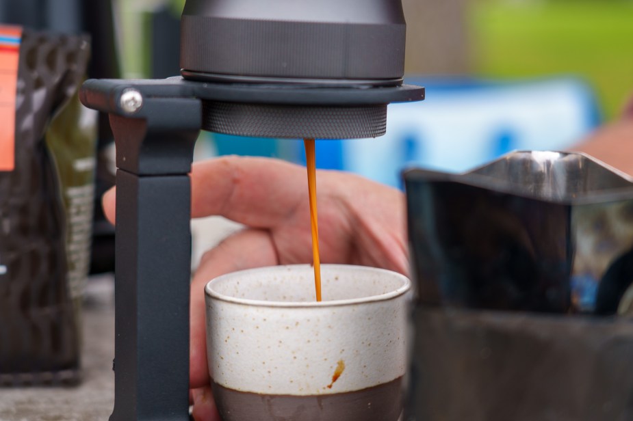 An espresso machine pulls a shot of espresso, which goes down in a straight stream to a small cup.