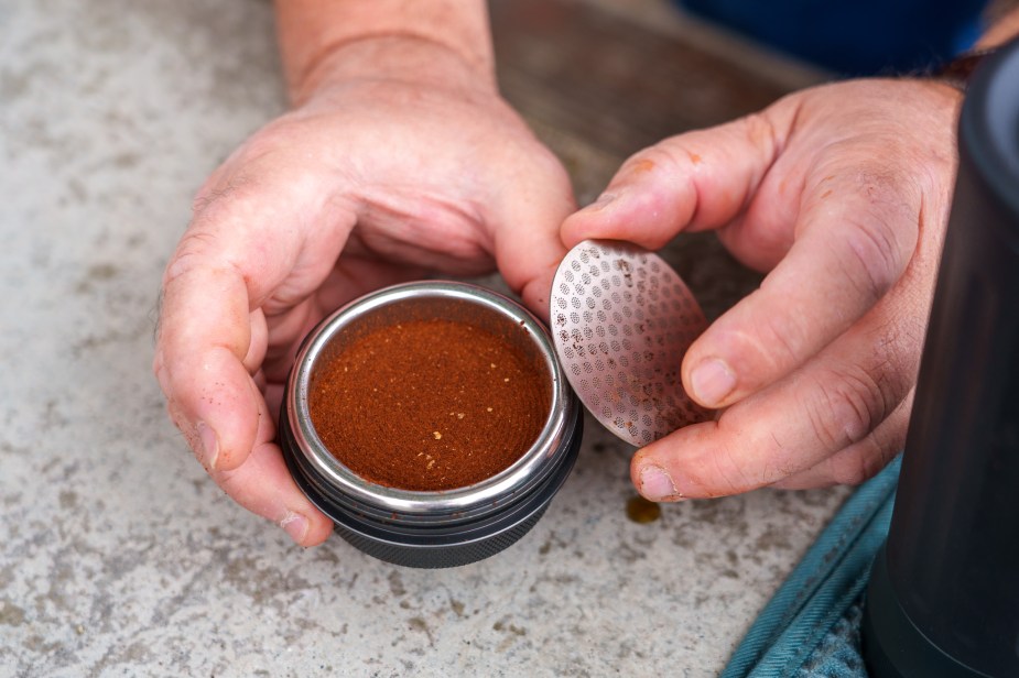 Closeup of a coffee filter basket containing ground espresso that has been tamped.