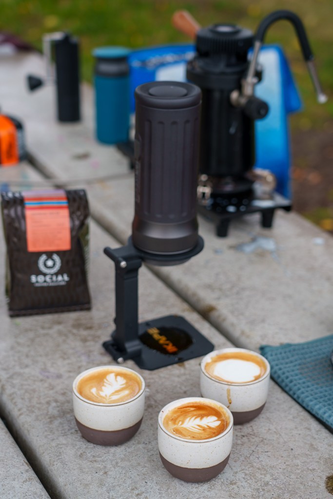 Three coffee drinks on a park bench.